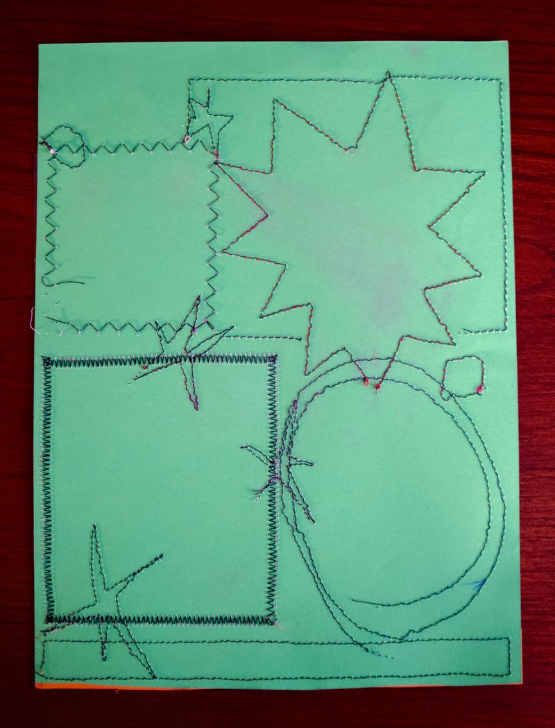Green paper with sewn line drawing in black thread